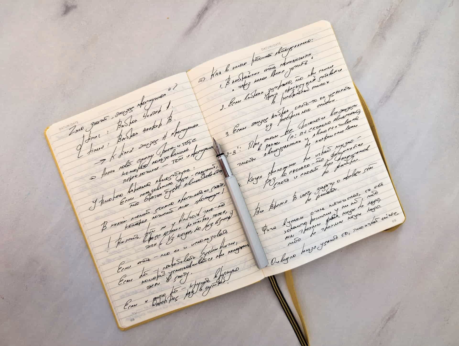 An open notebook with handwritten notes beside a pen