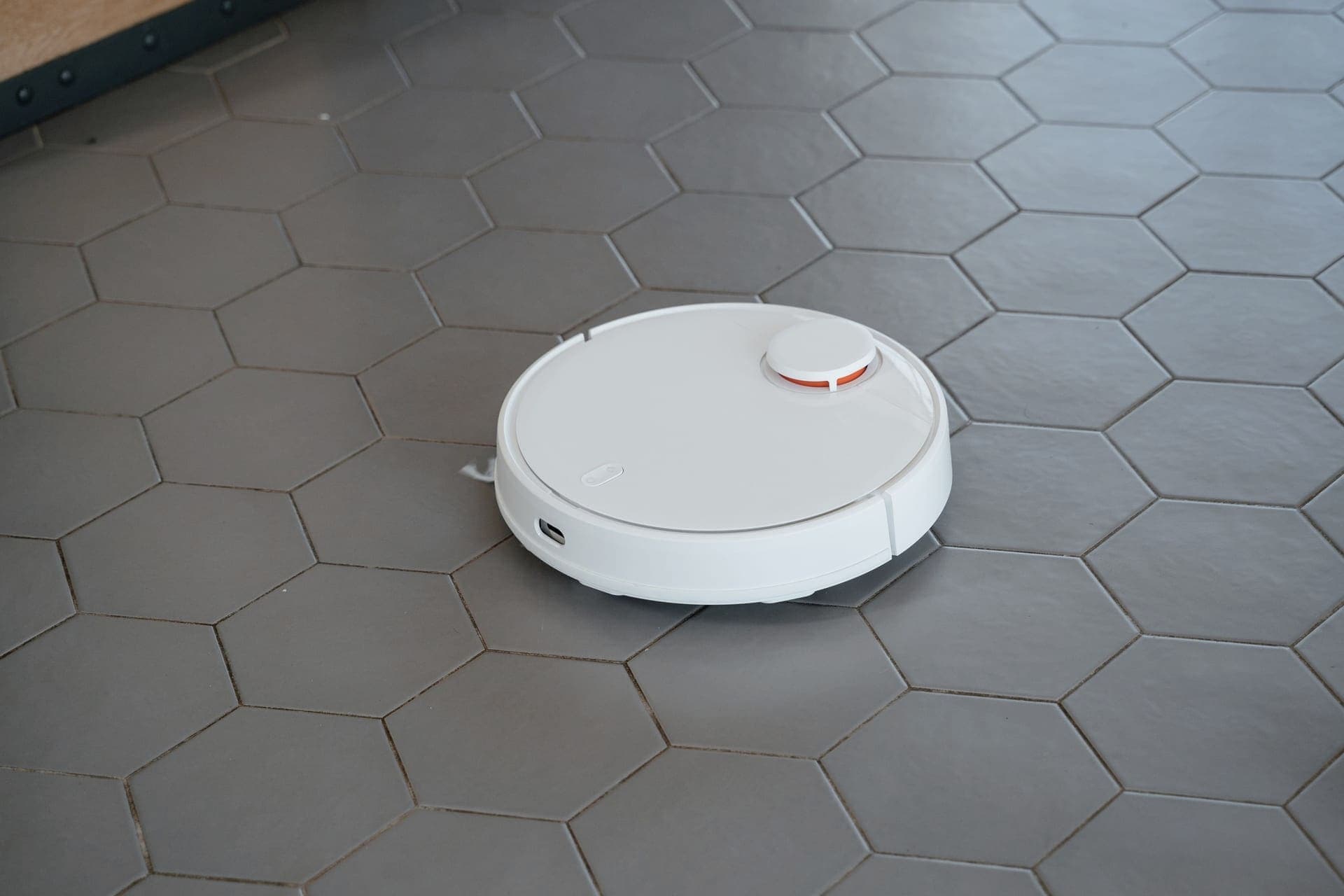 A robot vacuum on a hard floor beside a doorway